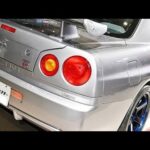 もはや「新車みたい」!? 日産「“R34”スカイラインGT-R」が大復活！ 25年以上前のクルマが裏の裏まで「サビ」も無しに？ 日産サービスセンターの「フルレストア」モデルの仕上がりが“段違い”だった